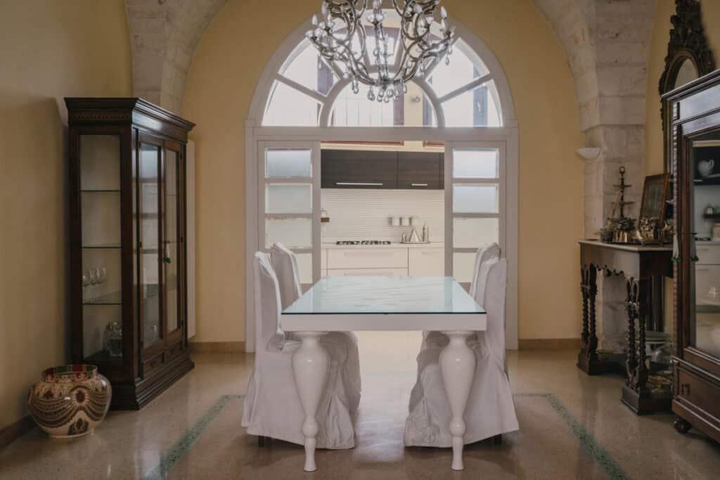 Sala da pranzo elegante con tavolo bianco e sedie rivestite in tessuto bianco.