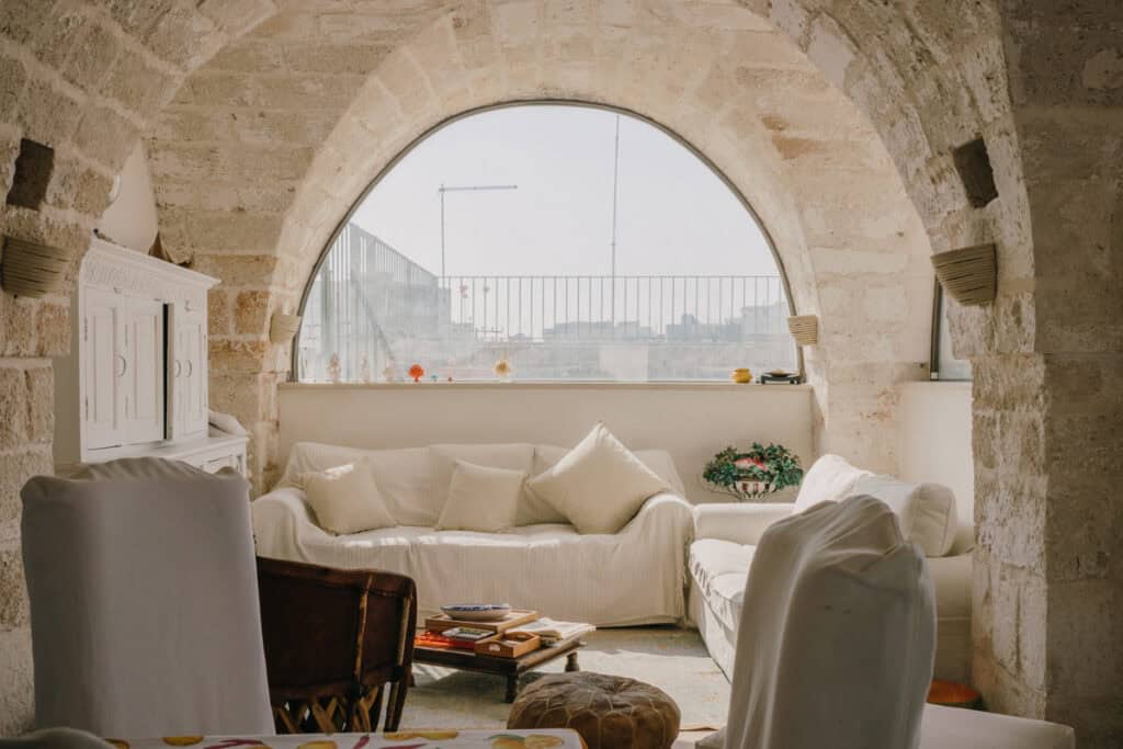 Salotto con grande finestra ad arco in pietra, arredamento elegante e accogliente.